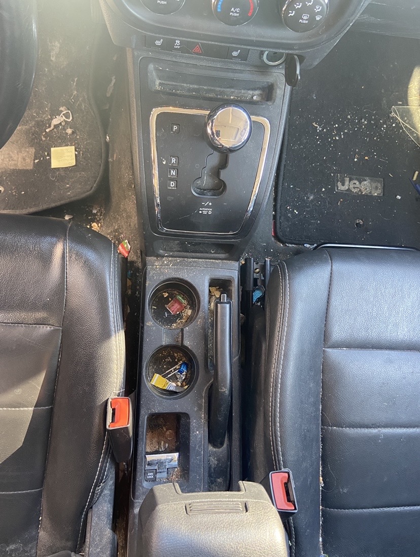 Jeep interior before detailing - cluttered center console with debris in cup holders